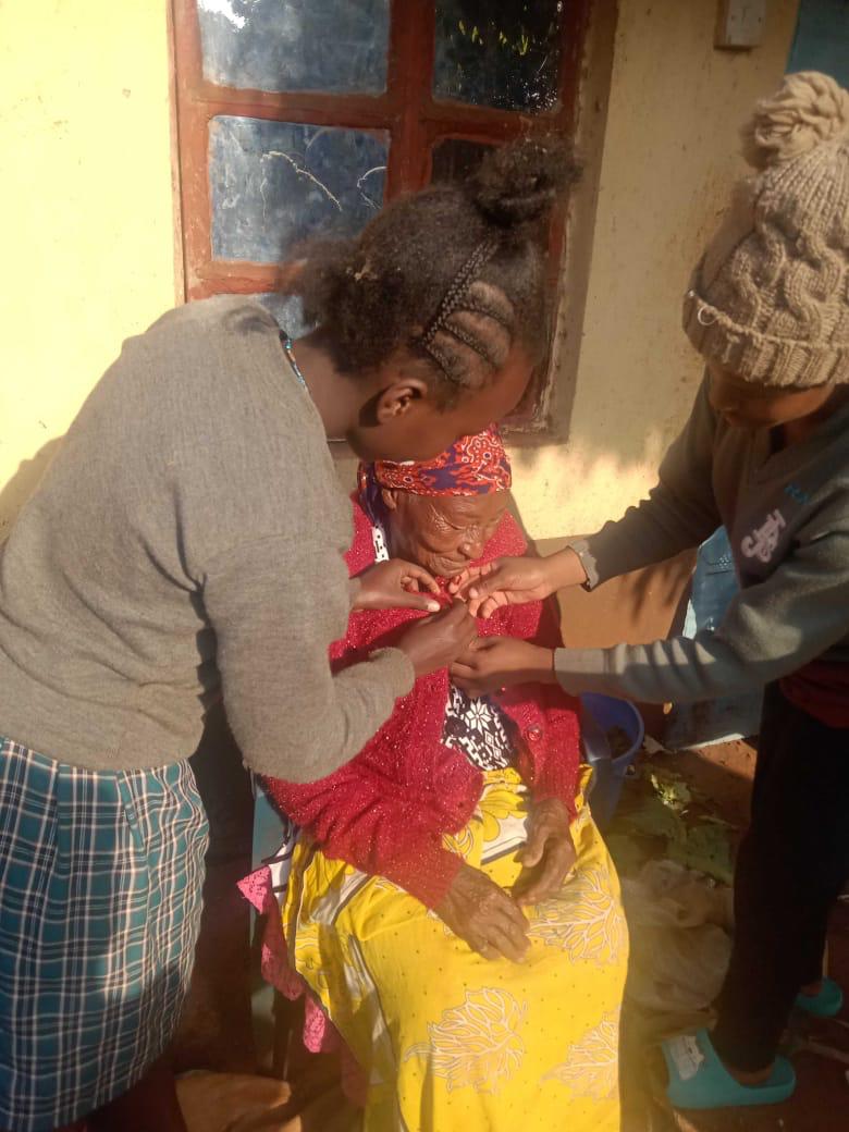 Volunteers supporting an elderly community member during a home visit